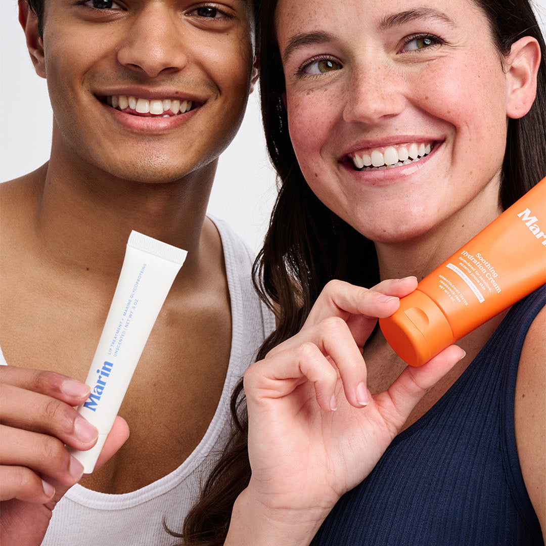 Two smiling people holding Marin skincare tubes in a close-up, showing product packaging