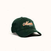 Front three-quarter view of forest green Marin dad hat embroidered with 'Marin' and 'MAINE' on light speckled background