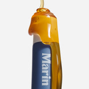 Blue tube labeled 'Marin' lip treatment with amber honey-like gel dripping over the cap