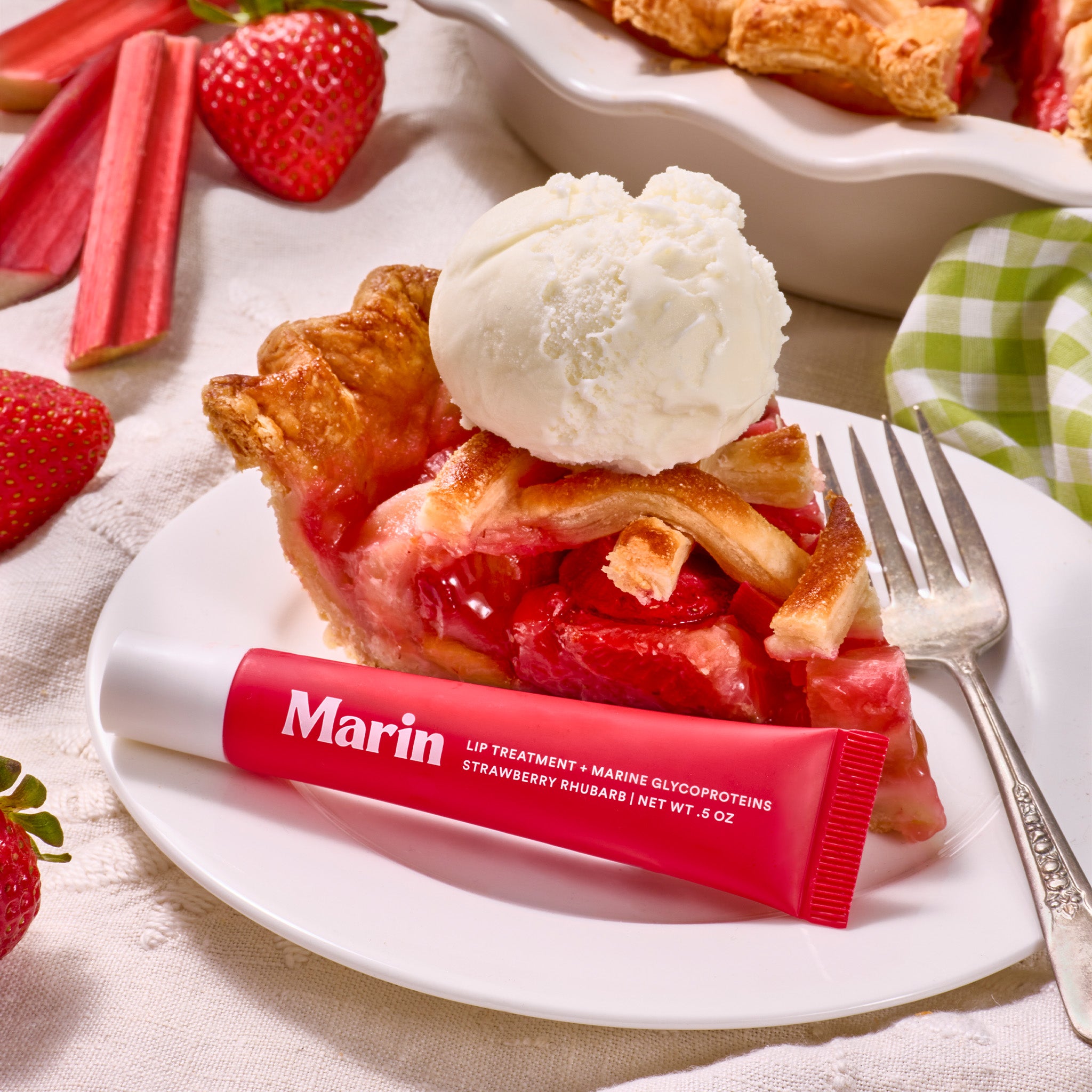 Red Marin lip tube reading Marin LIP TREATMENT + MARINE GLYCOPROTEINS STRAWBERRY RHUBARB NET WT .5 OZ with pie & ice cream