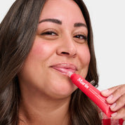Woman applying Marin lip treatment tube labeled: Marin LIP TREATMENT MARINE GLYCOPROTEINS STRAWBERRY RHUBARB NET WT. 0.5 OZ
