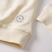 Cream sweatshirt cuff and hem with stitched square patch reading THINK OUTSIDE THE BOX