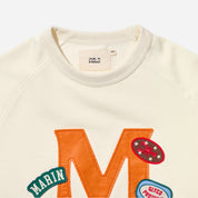Cream sweatshirt with large orange M, MARIN and GLYCO PROTE patches, label 'UNELD' and size tag 'XS'