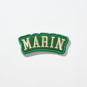 Green embroidered collegiate-style patch with cream letters reading MARIN