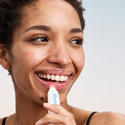Smiling woman applying Marin balm stick to her lower lip