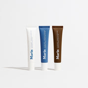 Three Marin lip treatment tubes: white (unscented), blue (blueberry tint), brown (caramel) on white background