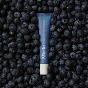 Blue tube of Marin lip treatment on blueberries