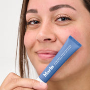 Person holding a tube labeled: Marin LIP TREATMENT + MARINE GLYCOPROTEINS BLUEBERRY FRENCH TOAST NET WT .5 OZ