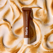 Marin tube labeled LIP TREATMENT + MARINE GLYCOPROTEINS CAMPFIRE S'MORES | NET WT .5 OZ on toasted-mallow background